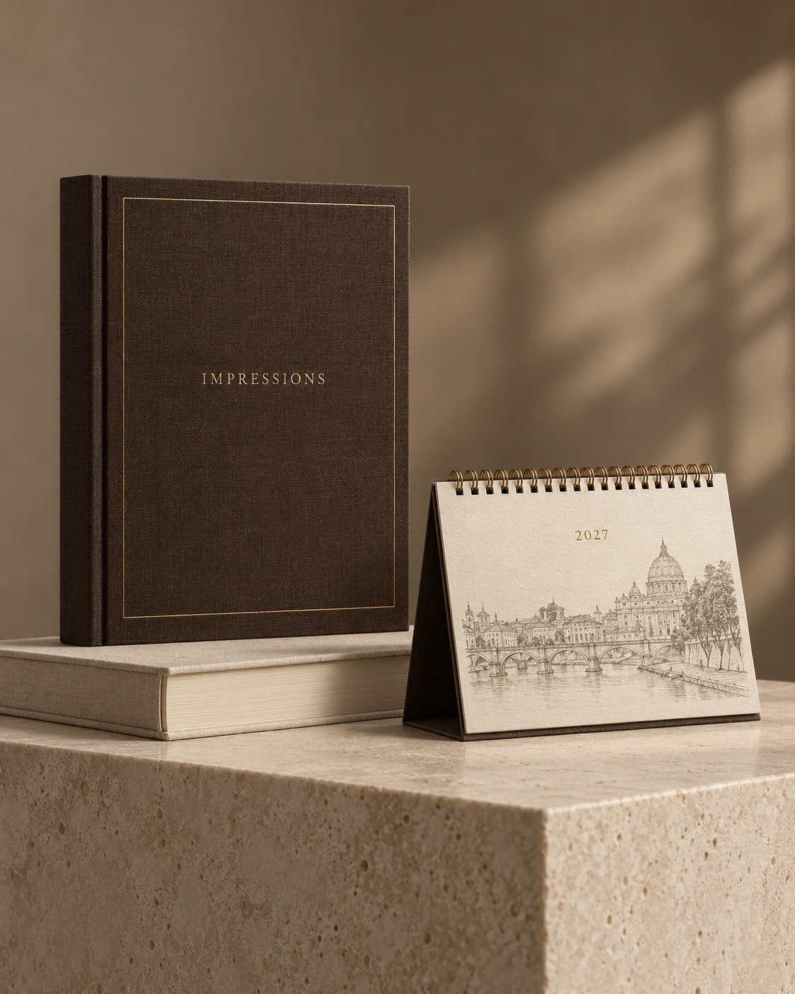 Styled concept of an espresso cloth-bound book and an ivory 2027 desk calendar